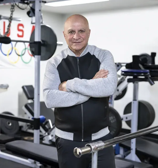 Man with arms crossed beside gym equipment