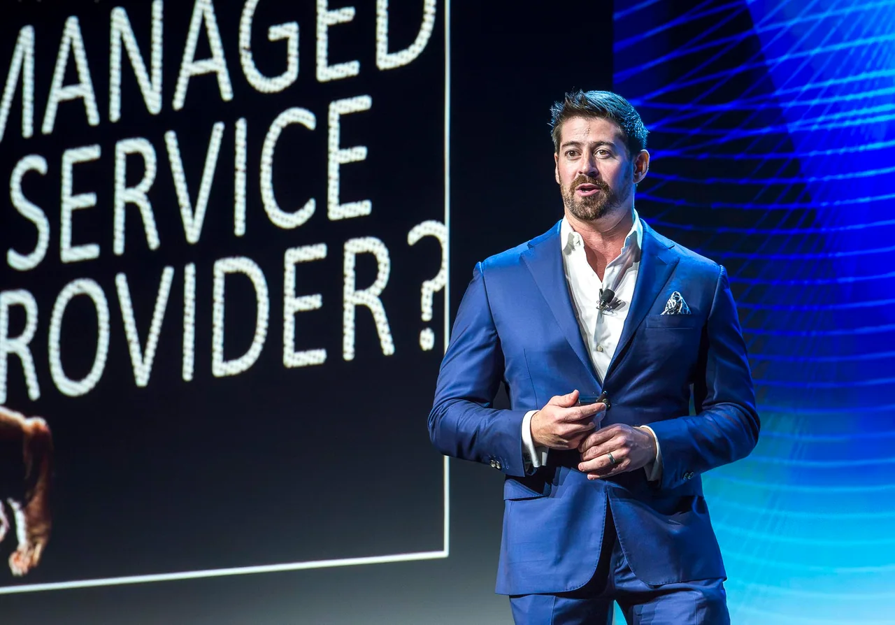 Speaker presenting in front of a blue technology backdrop