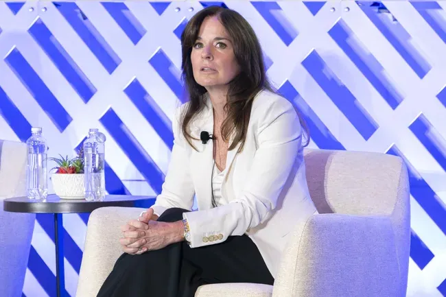 Panelist seated beside a table on a conference stage
