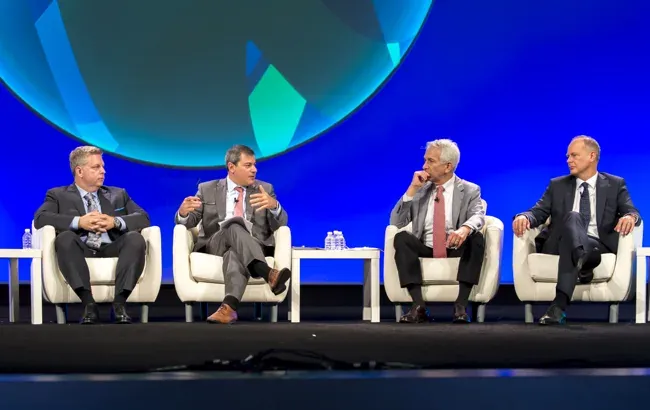 Four panelists seated on stage during a conference discussion
