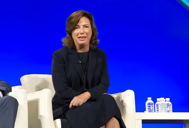 Seated speaker against a blue-lit conference backdrop