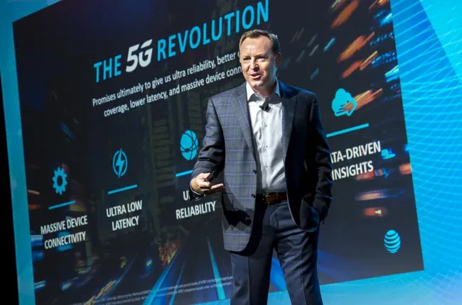 Speaker presenting on 5G technology in front of a conference screen