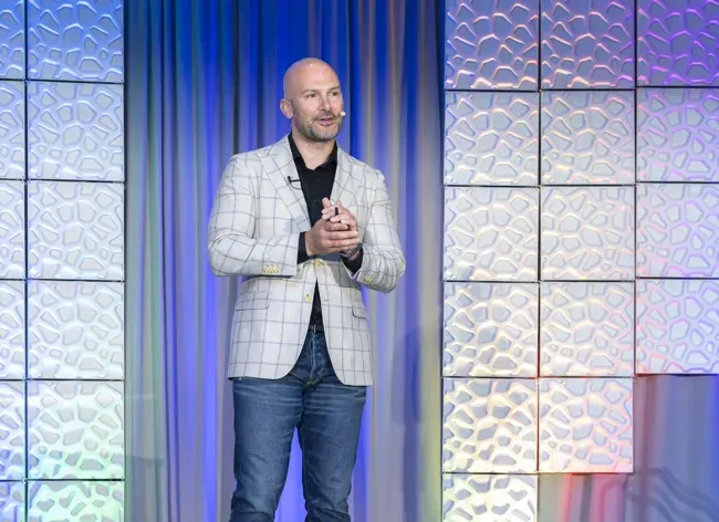 Conference speaker in a light blazer addressing the audience
