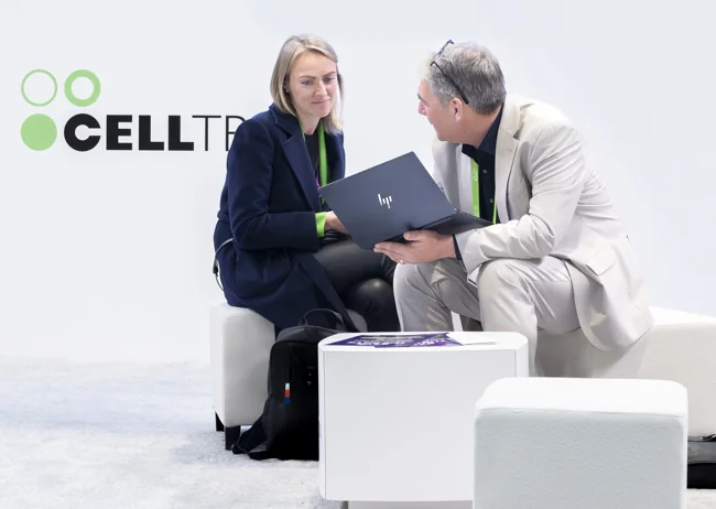 Two attendees reviewing a laptop together at an exhibition booth
